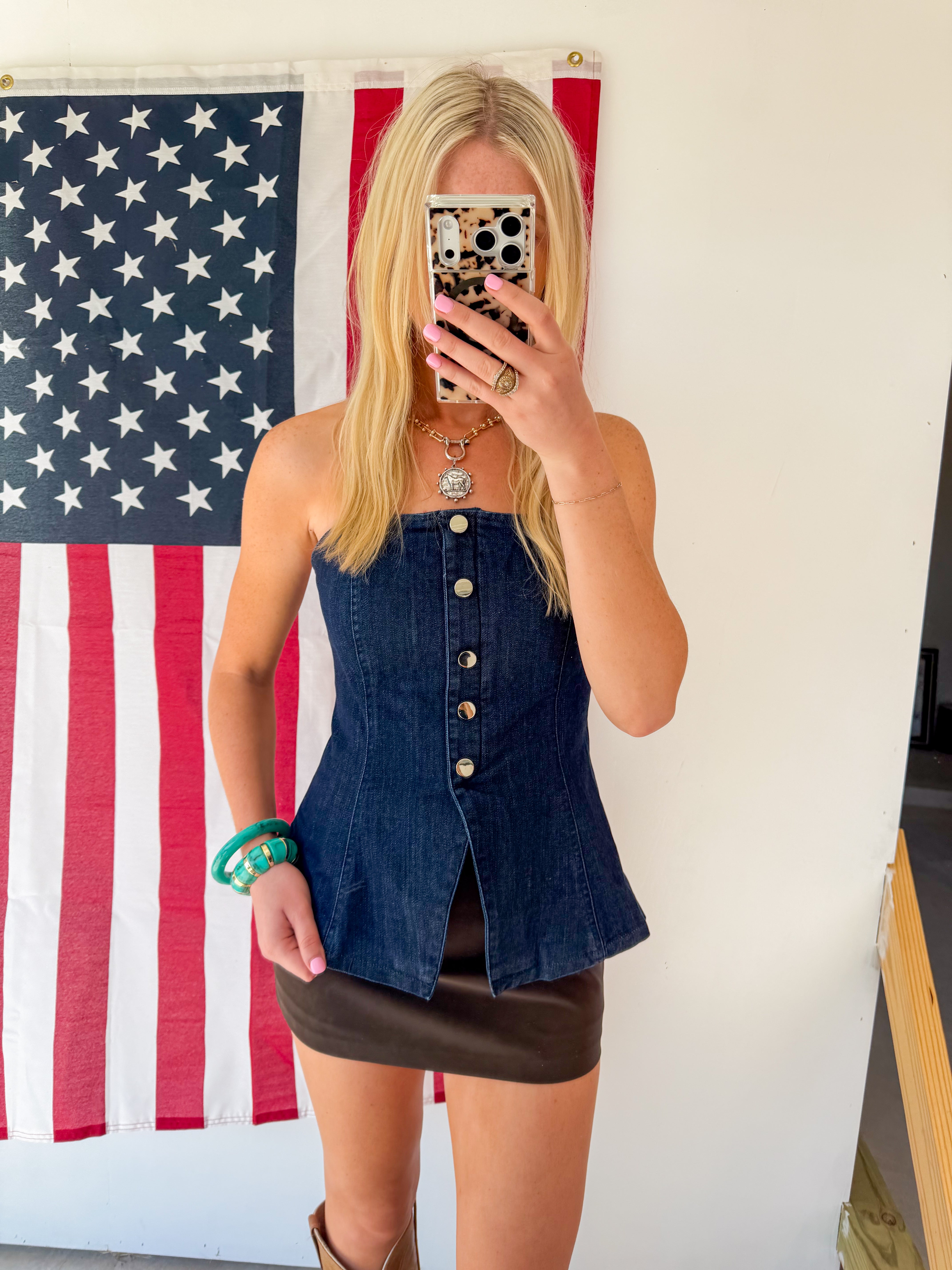 Person wearing a denim top and black skirt in front of an American flag