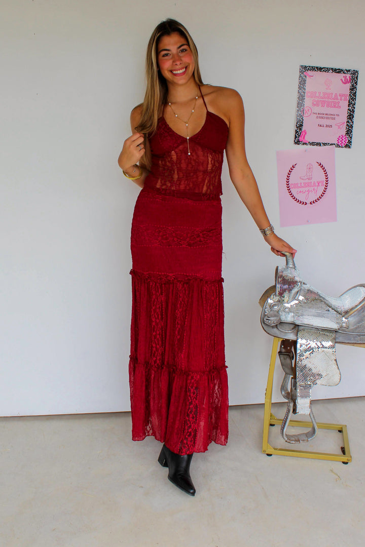 Woman in a red dress standing next to a whiteboard with a pink poster in an indoor setting.
